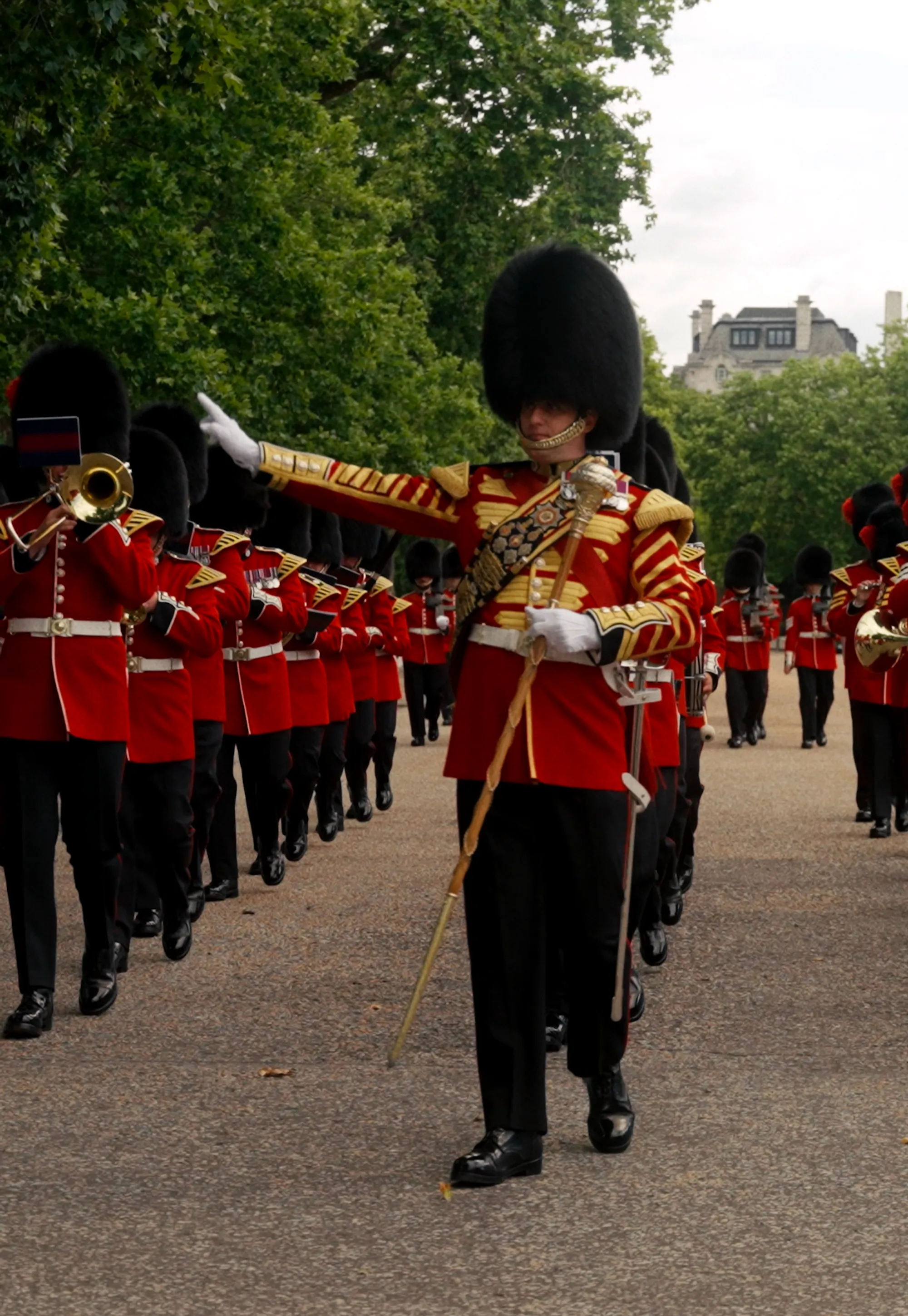 Grenadier Guards marching with instruments inside the military barracks with people looking from outside the fence