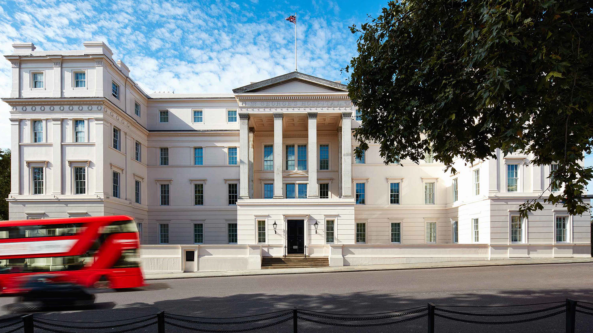 Front entrance of The Lanesborough Hotel with a red double-decker speeding past.