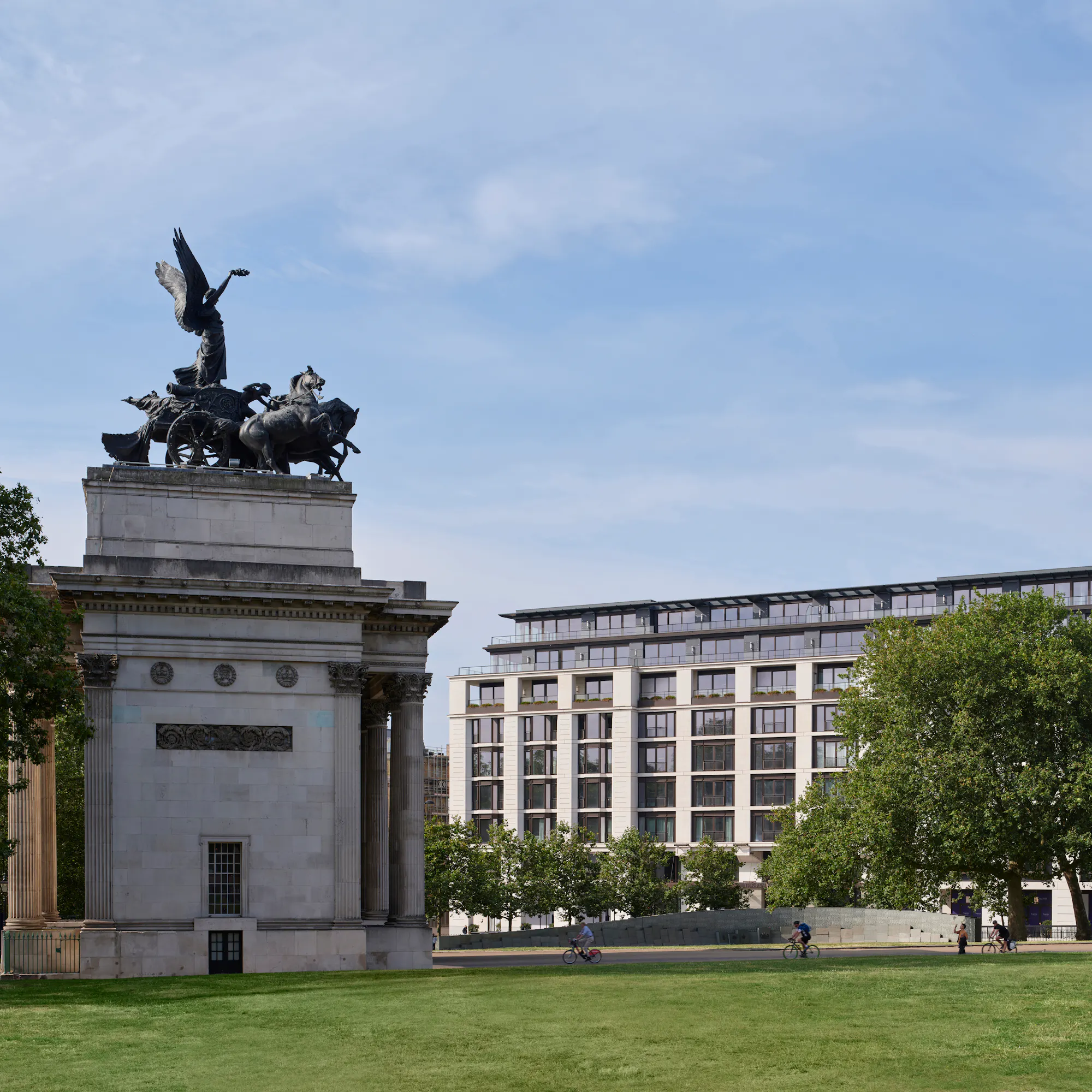 Wellington Arch's bronze Quadriga sculpture stands before The Peninsula London, across a green lawn.
