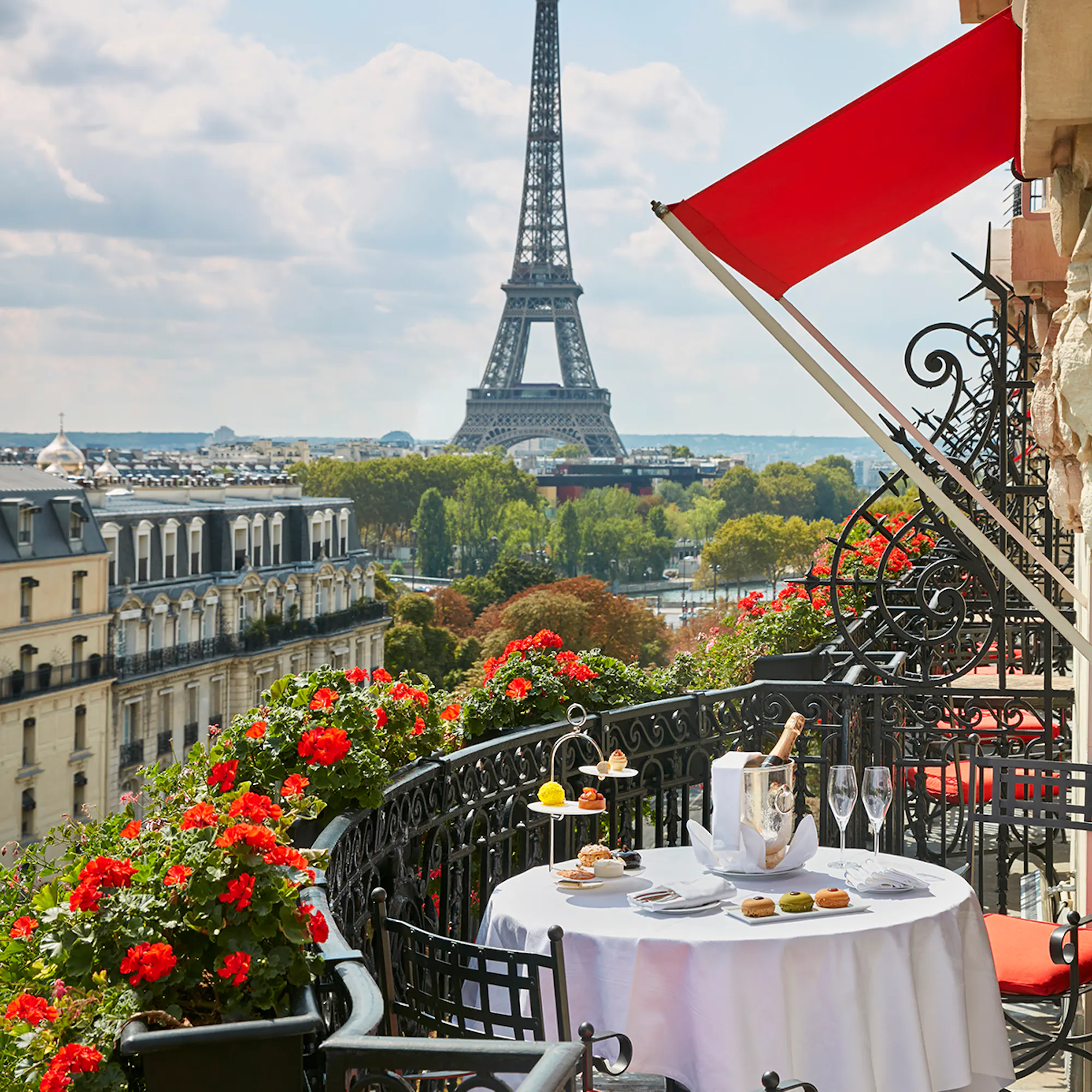The Eiffel Tower from a balcony at Hôtel Plaza Athénée, with red awnings and geranium-filled window boxes.