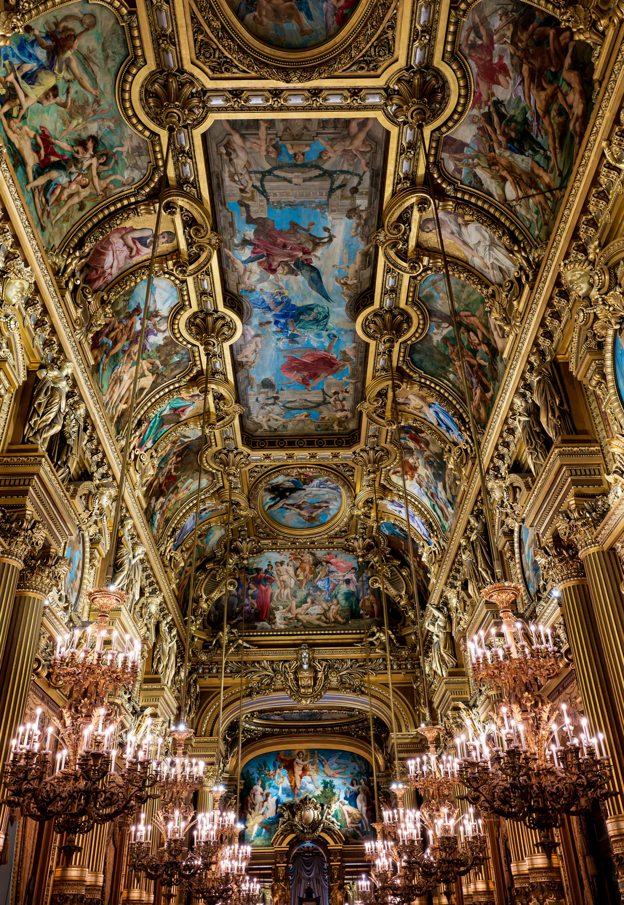 Painted ceiling of the Grand Foyer at Palais Garnier, Paris, illuminated by chandeliers.
