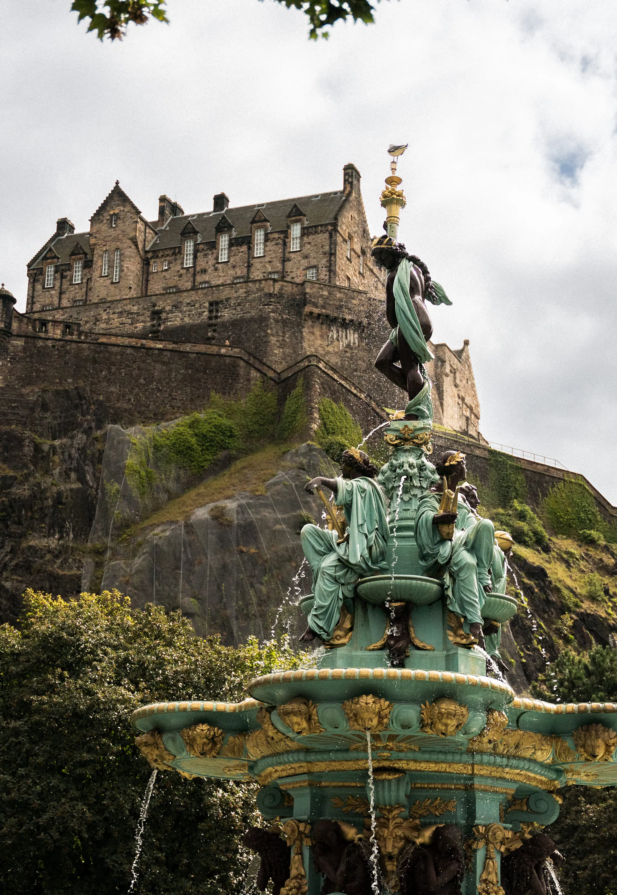 Edinburgh Castle atop its volcanic rock, seen past the ornate figures of the Ross Fountain.